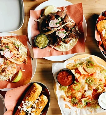 Tacos and sides shared on a wooden table