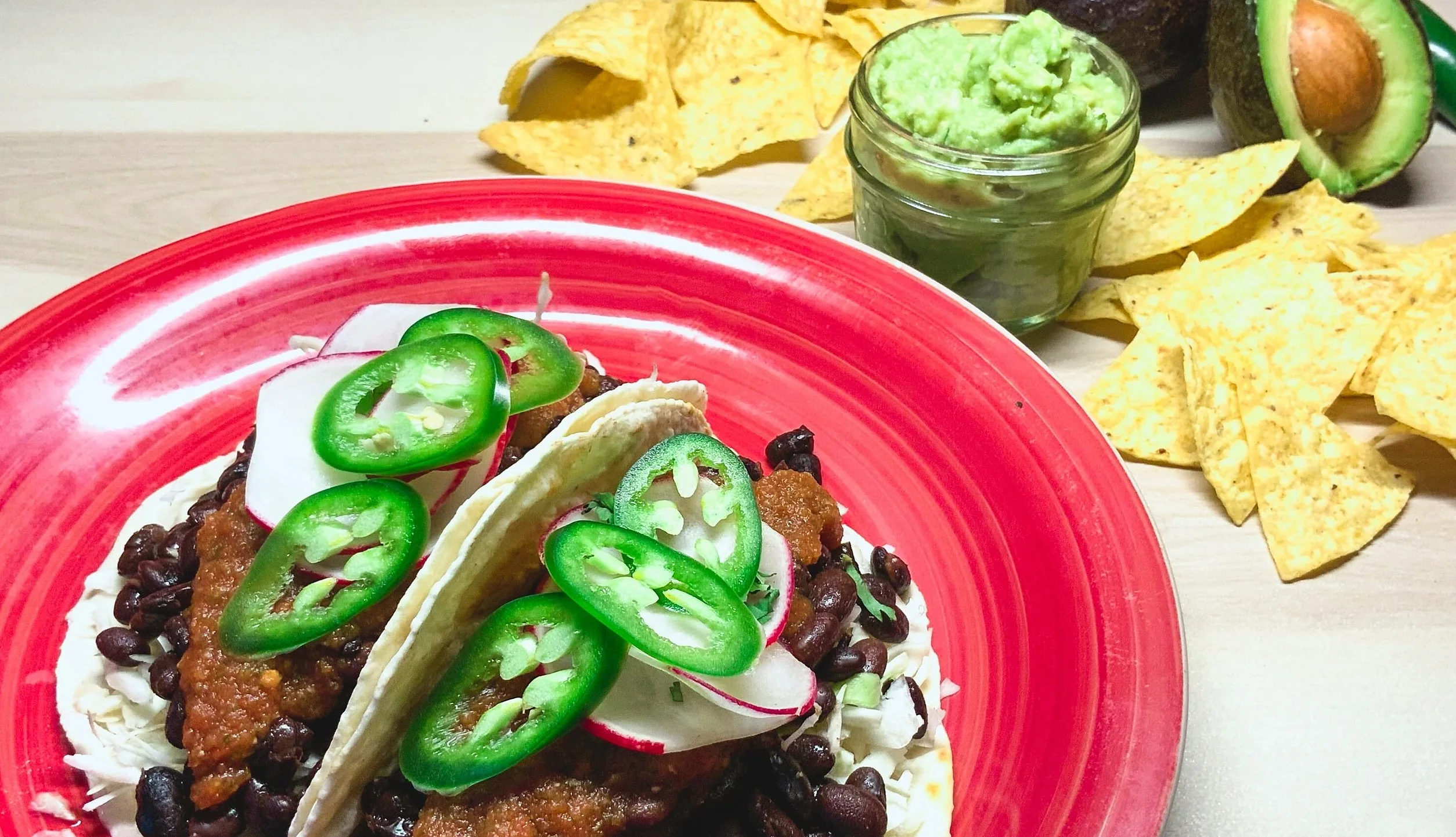 Rancheros tacos with black beans and jalapeño on a red plate