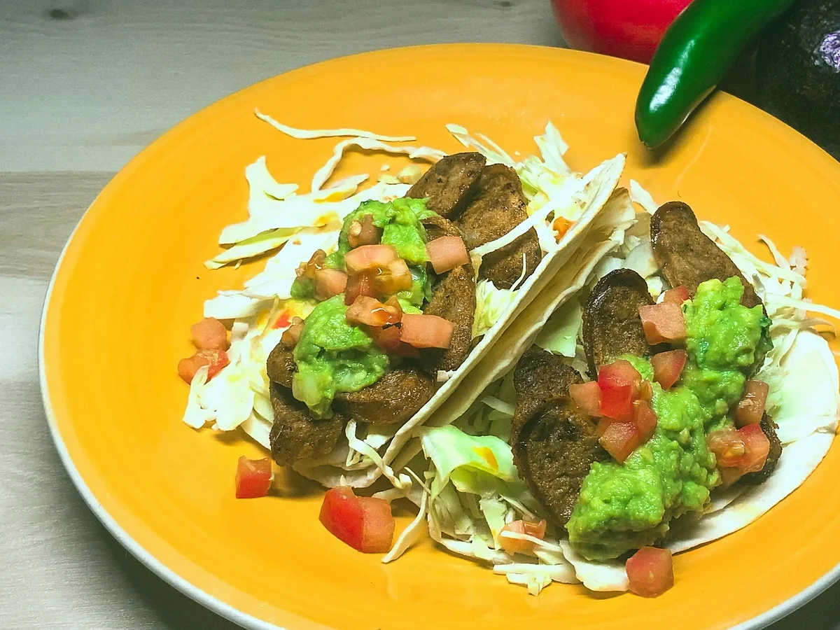 Chorizo tacos with guacamole and diced tomato on a yellow plate
