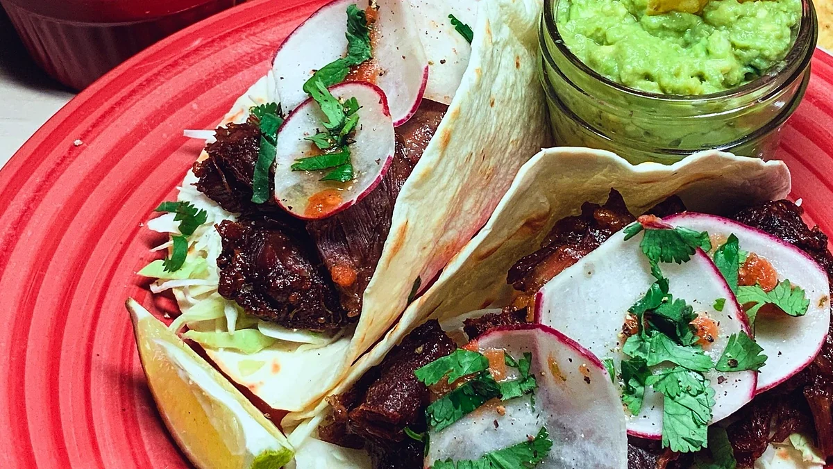 Carnitas tacos with confit pork, radish and cilantro on a red plate